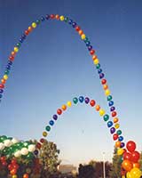 This 40 foot tall string-of-pearls style balloon arch is constructed in rainbow colors from equally spaced single balloons to visually carry the eye skyward.