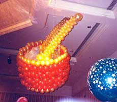 Balloon sculpture of a giant toy drum complete with drumsticks suspended from the ceiling