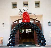 A giant two-story tall cowboy balloon sculpture with his bow legs stradling the entrance doors to a wewtern theme event